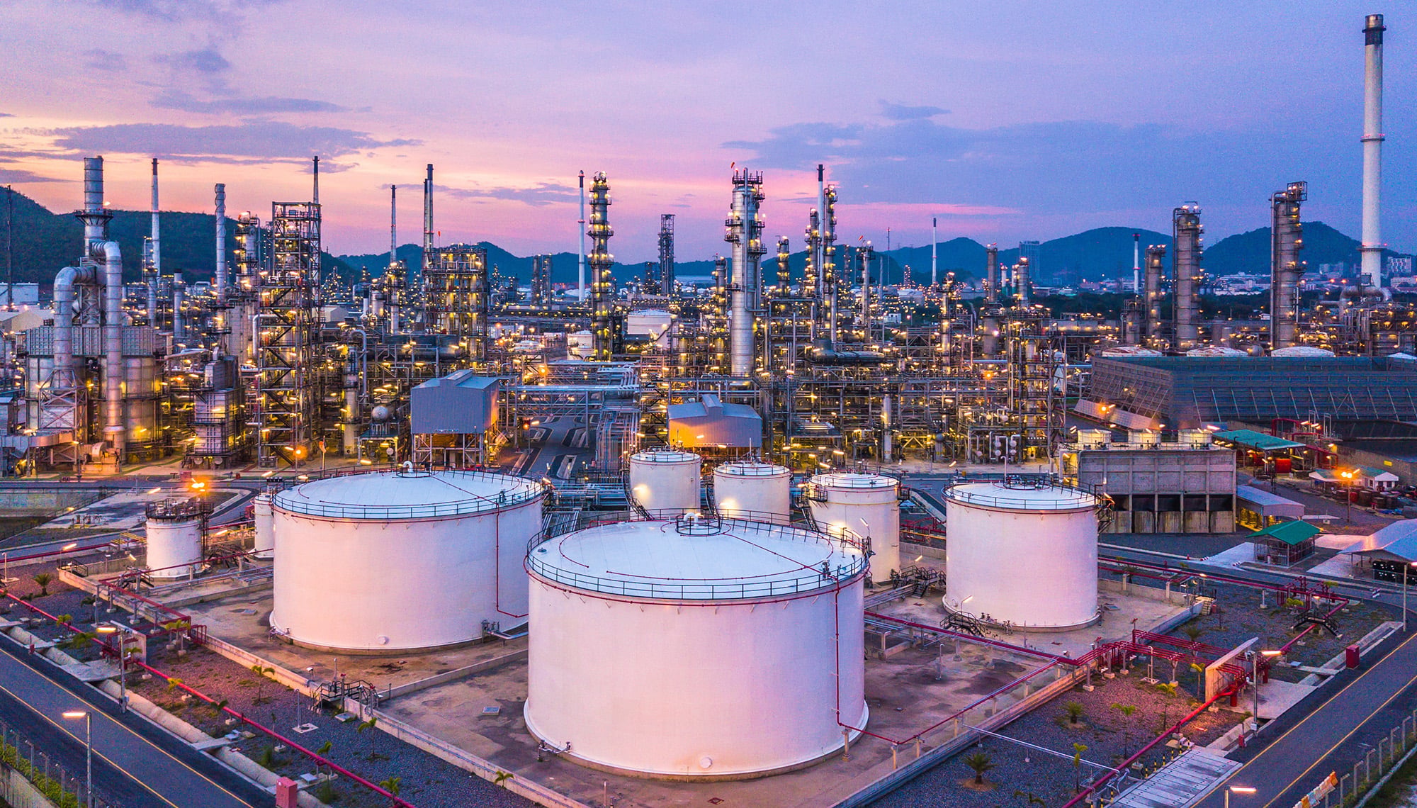 Large refinery showing tanks, towers, lights and mountains in distance